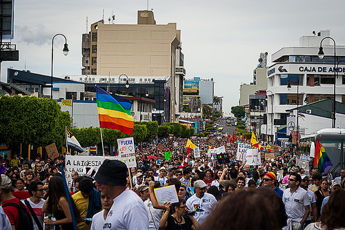 people marching down the main street with rainbow flags