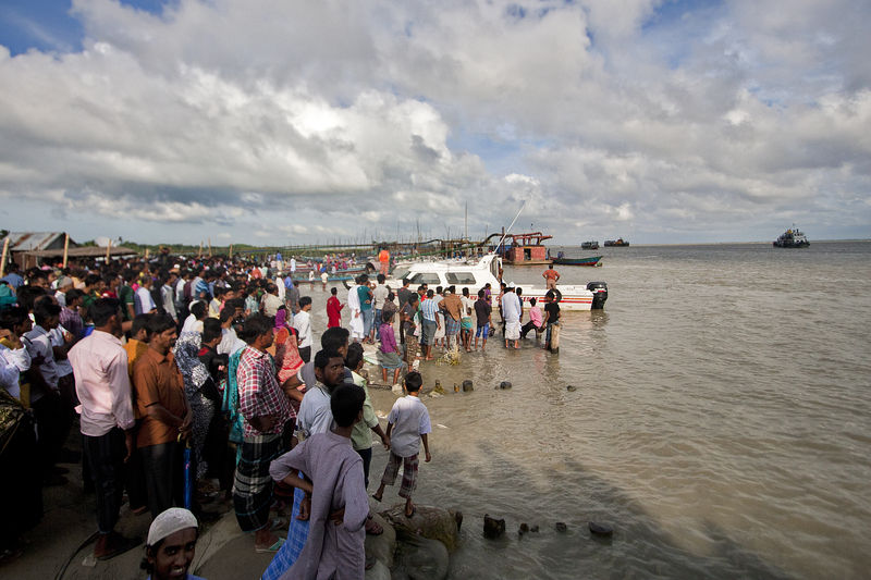 Bangladeshi onlookers gather near the scene where an overloaded ferry capsized in the Padma river in Munshiganj