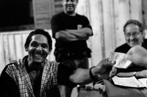 Ein zahnloser Arbeiter lacht laut, als er eine vollkommen legale Lohnzahlung erhält. Foto von Ricardo Funari.