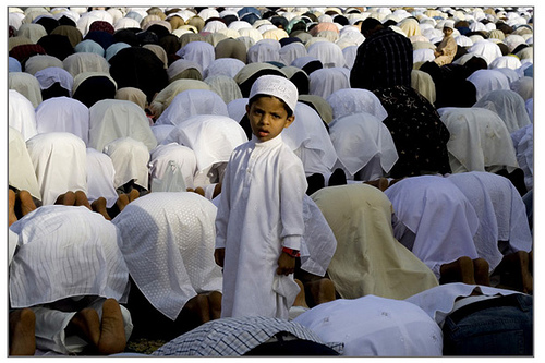 A boy looking behind while others are doing rituals at the end of Ramadan month, on Eid Namaaz (prayers) at Bangalore, India. Image by Sandip Devnath