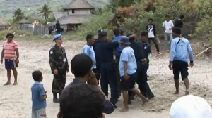 United Nations police officer watchs as Timorese police bash a local youth with fists, feet and a shotgun shoulder butt.