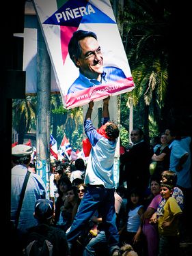 Man trying to take down Piñera electoral sign during Victor Jara's funeral, who was killed during the Pinochet dictatorship. Photo taken by Flickr user Amable Odiable and used under a Creative Commons license