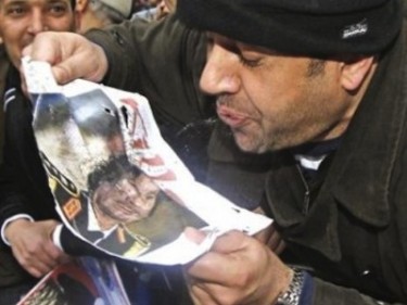 Un uomo sputa su una foto del Colonnello Gheddafi. Immagine pubblicata da @abanidrees.