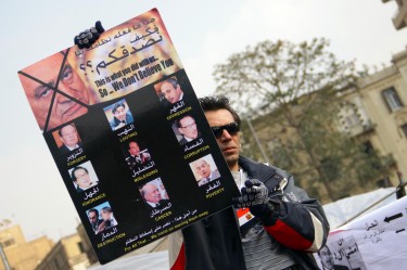 A protester in Tahrir Square, Cairo holds up a sign listing crimes of the Egyptian government against the people.