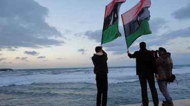 Des Libyens agitent leur drapeau au bord de la mer