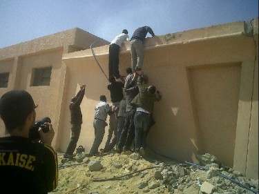 Protesters climbing the State Security building walls to try and save documents from burning