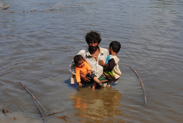 A man with his children under the water moving towards a safe place. Image by Rajput Yasir, copyright Demotix (16/9/2011).