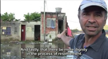 Jorge stands in front of his flooded house where his neighborhood used to stand. Documentary still.