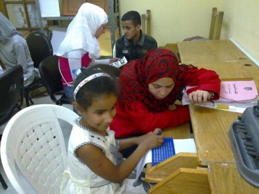 متطوعي جمعية رسالة يقومون بتدريس الطلبة المكفوفين القراءة