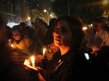 امرأة ترتدي أسود وتحمل شمعة حدادً على ضحايا أحداث ماسبيرو. تصوير عمرو جميل، من موقع ديموتكس