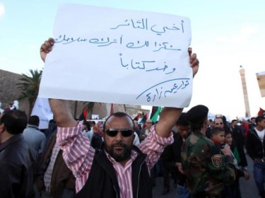 Ein Demonstrant trägt ein Schild mit der Aufschrift: Lieber Revolutionär, danke, dass du deine Waffe zuhause lässt und ein Buch mitbringst