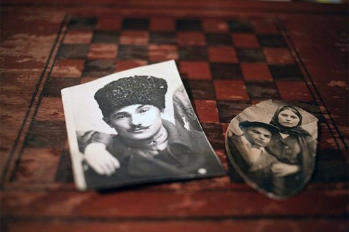 Foto's van Abdullah Gamidov, zijn vrouw Khalida, en haar vader Zia Chumidze liggen op het schaakbord in het huis van Gamidov in Kant, Kirgizië. Zia Chumidze vocht aan de frontlinie tijdens de deportatie en is nooit thuisgekomen. © Temo Bardzimashvili