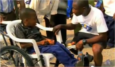Yeboah mentre spiega a un bambino sulla sedia a rotelle come superare la sua invalidità. Fotogramma tratto dal documentario Emmanuel's Gift