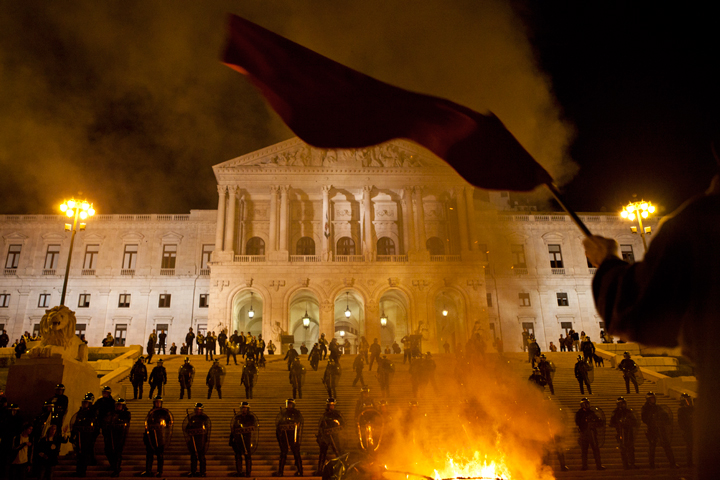 "Riot police monitor protests as a fire burns in front of the parliament building as demonstrations take place over government imposed austerity measures designed to ease Portugal's economic and financial crisis". Photo by João Caetano copyright Demotix (15/10/2012)