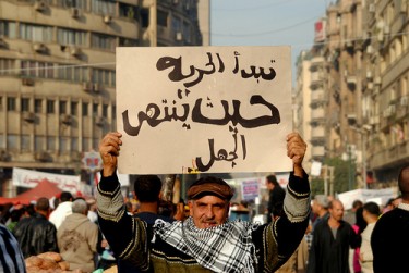 A man carries a poster which reads: Freedom starts where ignorance ends 