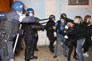 Agentes da polícia apontam bastões enquanto uma mulher sangra do nariz durante os confrontos. Foto de Pedro Nunes copyright Demotix (14/11/2012)