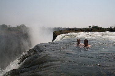 Swimming at the edge of Victoria Falls in a naturally formed safe pool, accessed via Livingstone Island. Image on Wikimedia Commons, released into public domain by Ian Restall.