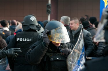 Policeman in Skopje, Macedonia, wipping splashed egg from helmet.
