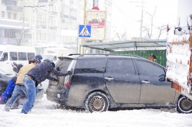 Kyiv residents help push a car stuck in the snow. Photo by jonatha borzicchi, copyright © Demotix (22/03/13).
