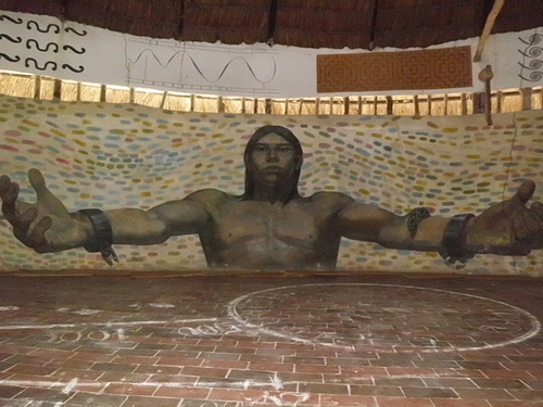  Un  murale raffigurante "Kiwxi&quot, leader indigeno ucciso in Brasile, la cui immagine decora il muro interno della churuata. Foto di Akaneto.