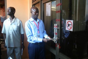 Head Of security at Daily Monitor opens the door after the reopening. Photo from Daily Monitor official Facebook page