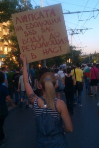 A protester in Sofia carries a sign saying: "The lack of evolution in you leads to a revolution in us!" (Photo used with permission)