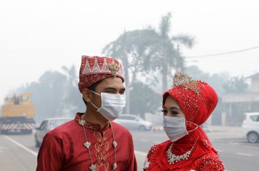 Жених и невеста из г. Муара в южном штате Джохор на границе с Сингапуром. Из-за смога им пришлось провести день свадьбы в защитных масках. Фото Lens Hitam, авторское право @Demotix (22/06/2013 г.) 