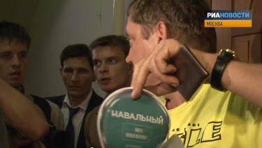 A Just Russia deputy demonstrates a pro-Navalny sticker found at the activist flat. YouTube screenshot.