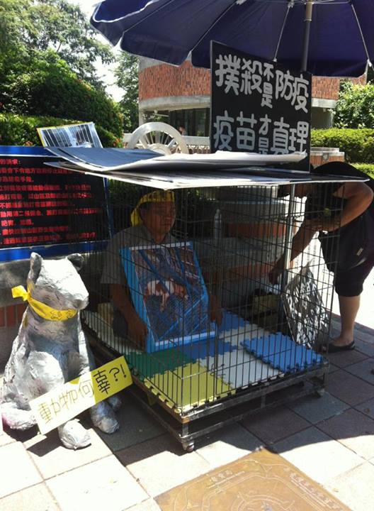 An animal right activist locked himself in an animal cage outside Council of Agriculture against the killing of stray dogs and cats to prevent the spread of rabies. He advocates for vaccination. Photo from 張敬偉 Facebook.