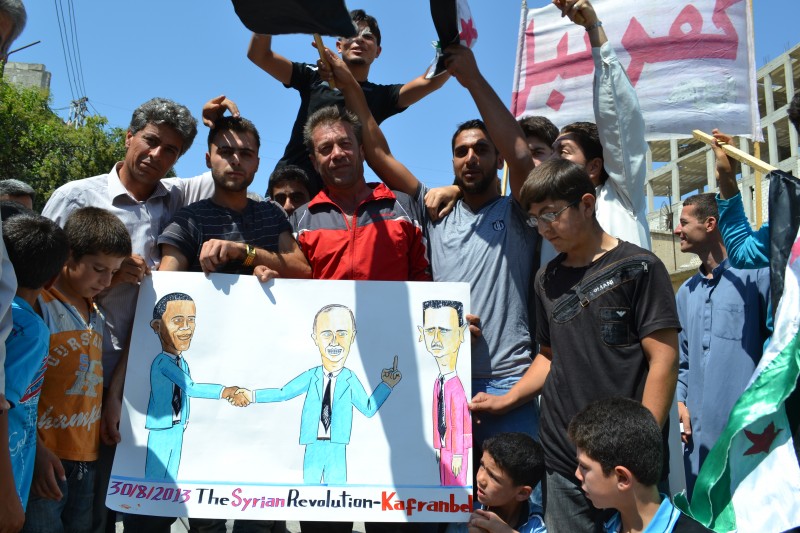 Syrian protesters carry banners calling for international action against the Assad regime in Kafranbel, Idlib, in northern Syria. Image by Majid Almustafa. Copyright Demotix August 30, 2013