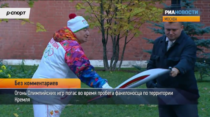 A guard lights the Olympic torch with a lighter during the relay through Kremlin. YouTube screenshot.