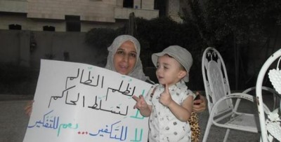 Suad Nofal with a child and one of her banners in Raqqa. Source: Suad Nofal´s facebook page.