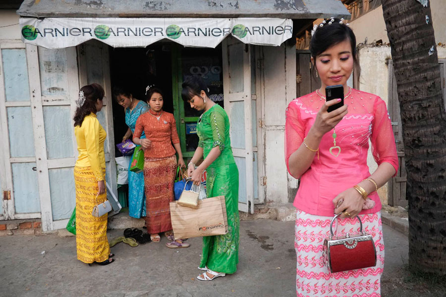 Estudantes universitários saindo de um salão de beleza cheio em Myanmar