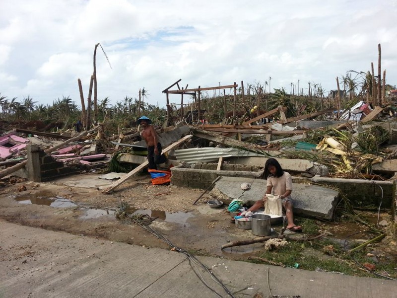 A woman washing clothes amid the debris after the storm. Photo by David Yu Santos, Facebook