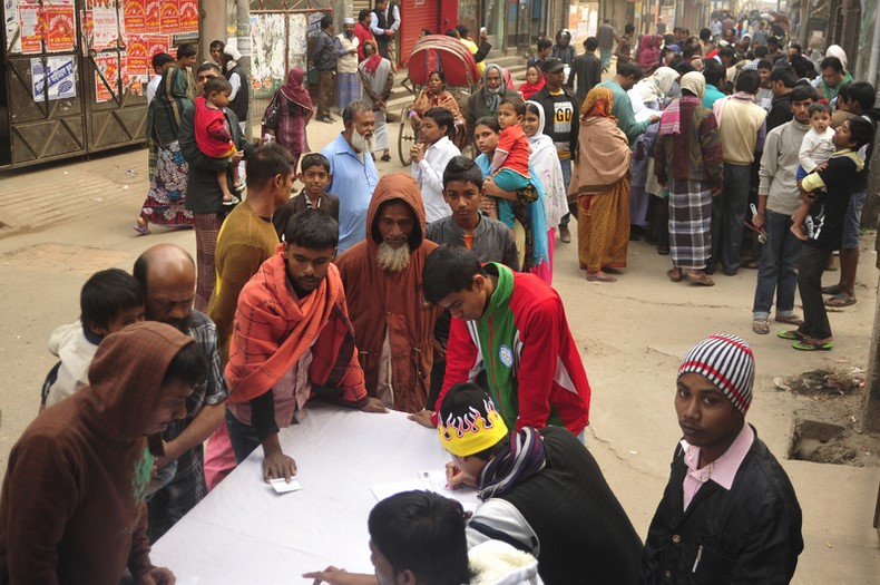 Voters surround a polling agent to collect their voting number in Dhaka-6 constituency during the 10th National Election. Image by Firoz Ahmed. Copyright Demotix (5/1/2014)