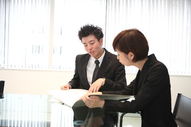 Photo of Japanese male employee and female employee working in office, discussing plans. Rroyalty free photo