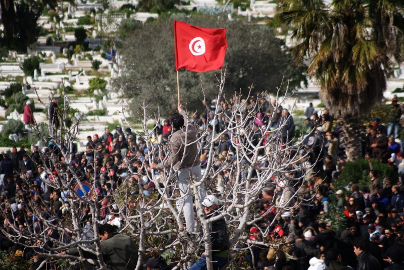 Demonstrant met Tunesische vlag bij begrafenis van Belaid. Foto: Elyes Jaziri (gebruikt met toestemming)