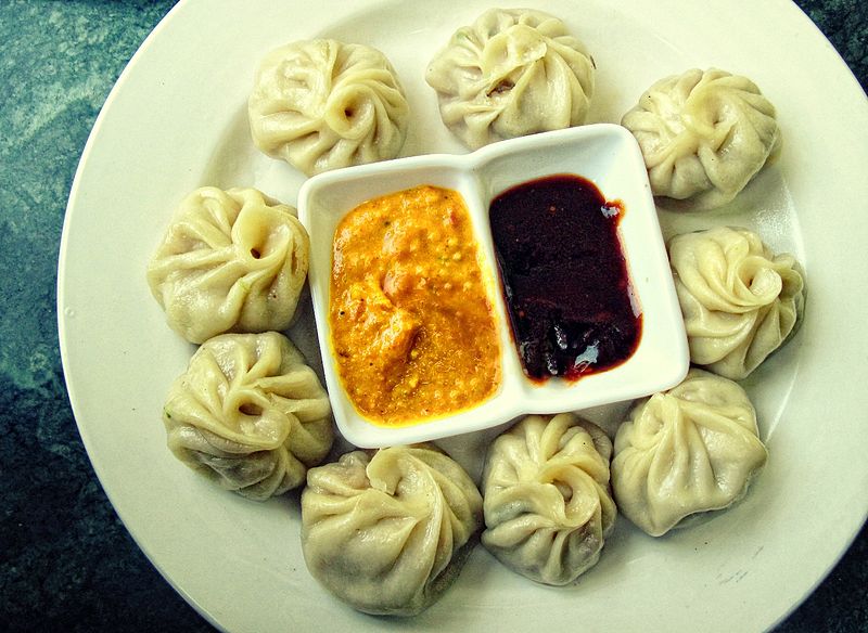 A typical serving of a plate of Momo with Sesame Yellow Sauce and Red Ginger Chilli Sauce in Nepal. Image from Wikimedia Commons by Kushal Gayal. CC BY-SA