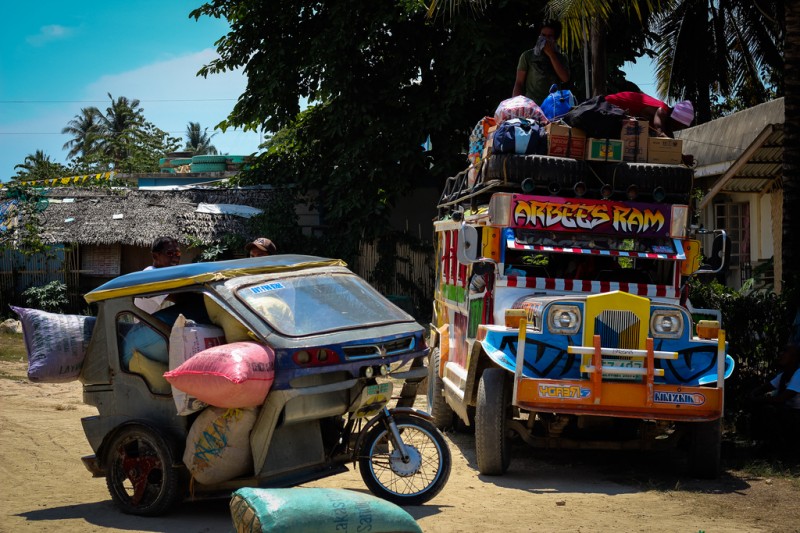 A jeepney beside a trike which is also a popular mode of transportation in the Philippines. Flickr photo by Victor Dumesny (CC License)