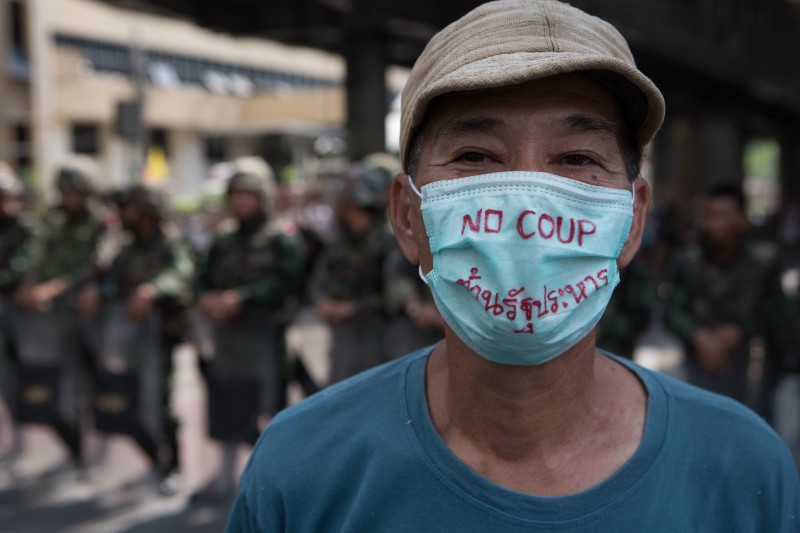 A protester stands in front of a line of soldiers in Bangkok while wearing a mask bearing the message 'No coup'. Photo by Atiwat Silpamethanont, Copyright @Demotix (5/25/2014)