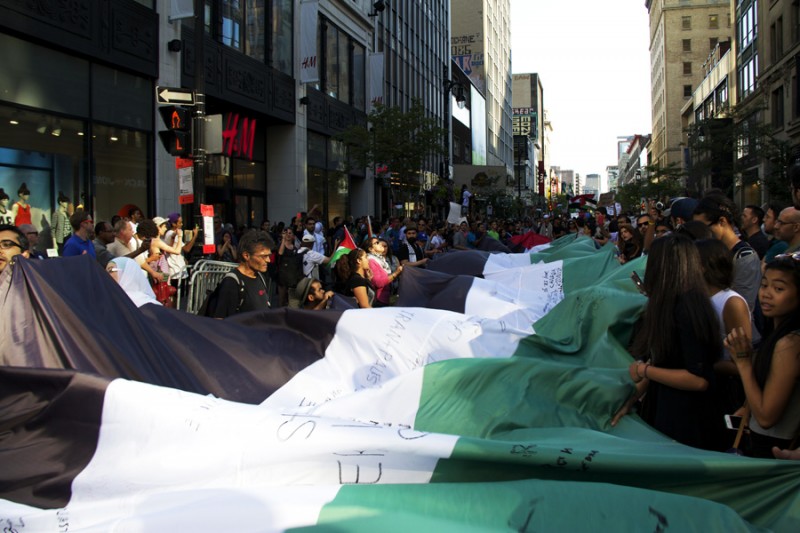 "Manifestantes em Montreal erguem a mais longa bandeira da Palestina de todas durante protesto de solidariedade à Gaza na sexta-feira, 11 de julho 2014."