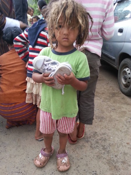 A little girl with a pair of recycled shoes during distribution in Ghasa. Image used with permission.
