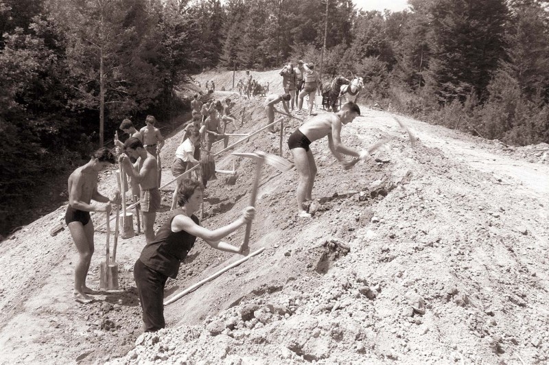 متطوعون يعملون على ترميم طريق ريفي في سلوفينيا ضمن مبادرة العمل الشبابي عام ١٩٦٠. الصورة عن موقع عام