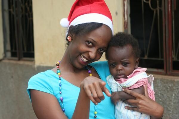 La fondatrice de 40 jour pour 40 sourires, Esther Kalenzi, tenant un bébé pendant la campagne #BeSanta. Photo utilisée avec sa permission.