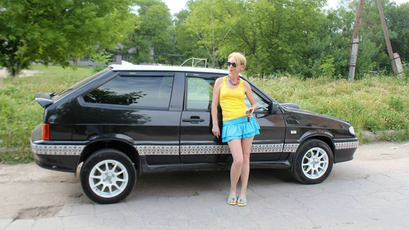La blogueuse Liza Bogoutskaïa pose devant sa voiture en minijupe, débardeur et lunettes de soleil.