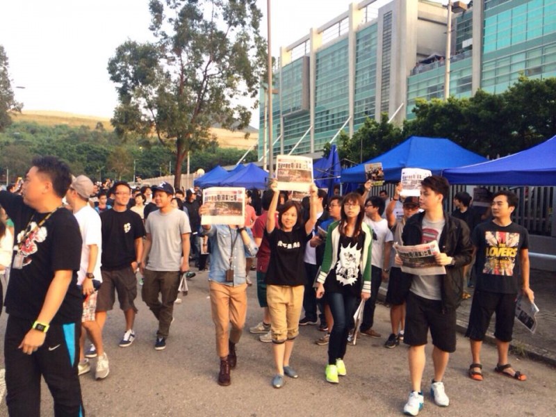 Zaměstnanci Apple Daily se postavili davu před svou centrálou a drželi před sebou své noviny. Fotografie z Faceboku, účet uživatelky Chan Pui Man.