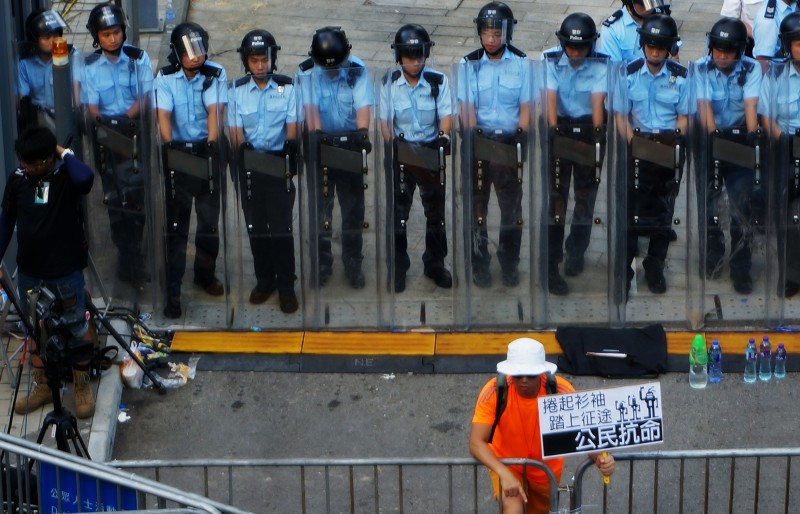 27. září 2014. Protestující držící ceduli „občanské neposlušnosti“ před nastoupenou řadou pořádkových policistů v rámci protestu „Okupujte Central“ před vládním úřadem ve čtvrti Admiralty. Autor fotografie P. H. Yang. Copyright Demotix.