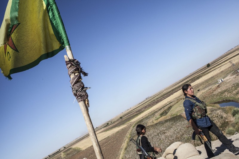 Dos milicianas del YPJ,  grupo afiliado con un grupo afiliado con las Unidades de Autodefensa Populares (YPG)Dos mujeres armadas, miembros de las YPJ, un grupo afiliado con las Unidades de Autodefensa Populares (YPG), pasea por la bases cercana a  Ras al-Ayn, una localidad kurda en el norte de Siria. 11 de octubre de 2013. Foto de Younes 