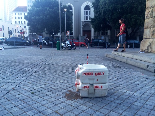 A portable toilet known to Cape Town's poor residents as a "porta-porta" or a "laptop". The toilet was used as a disruptive installation Brundyn+ Gallery and Open City (Church Square) in Cape Town. Image source: http://tokolosstencils.tumblr.com/