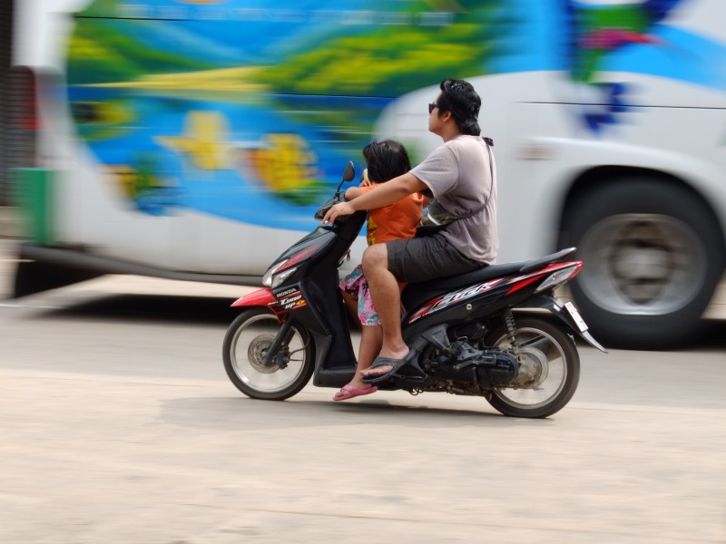 Ačkoli thajské zákony vyžadují povinné nošení helmy, řidič i jeho pasažér zjevně zákon ignorují. Autor fotografie Matthew Richards, copyright @Demotix (10/6/2012).